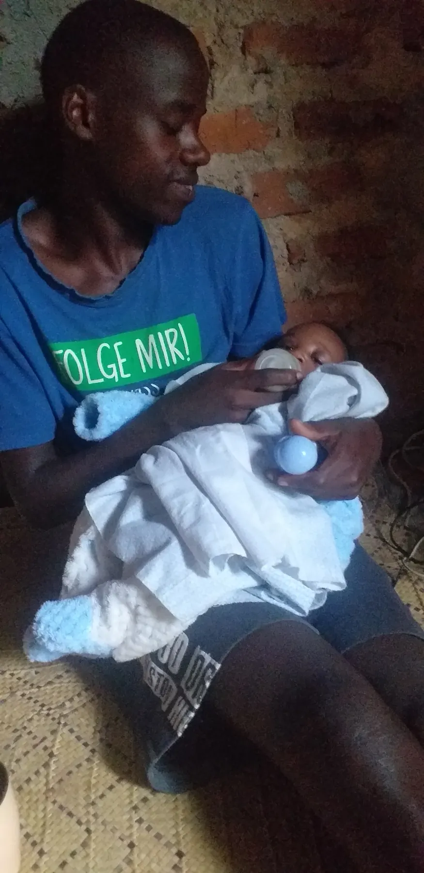 A young caregiver holding a baby indoors